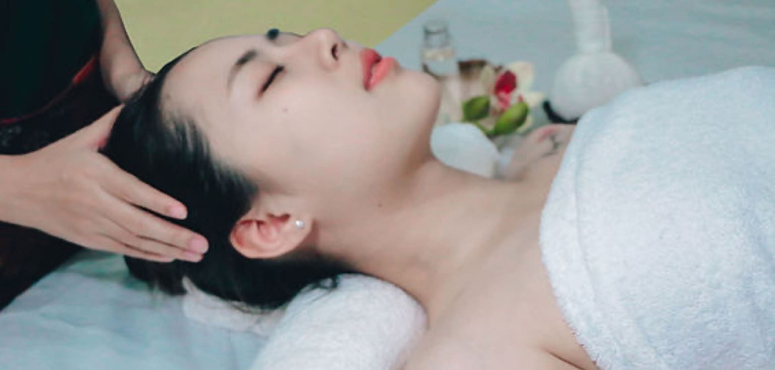 Masseuse masseert het hoofd en de nek van een vrouw op de behandeltafel