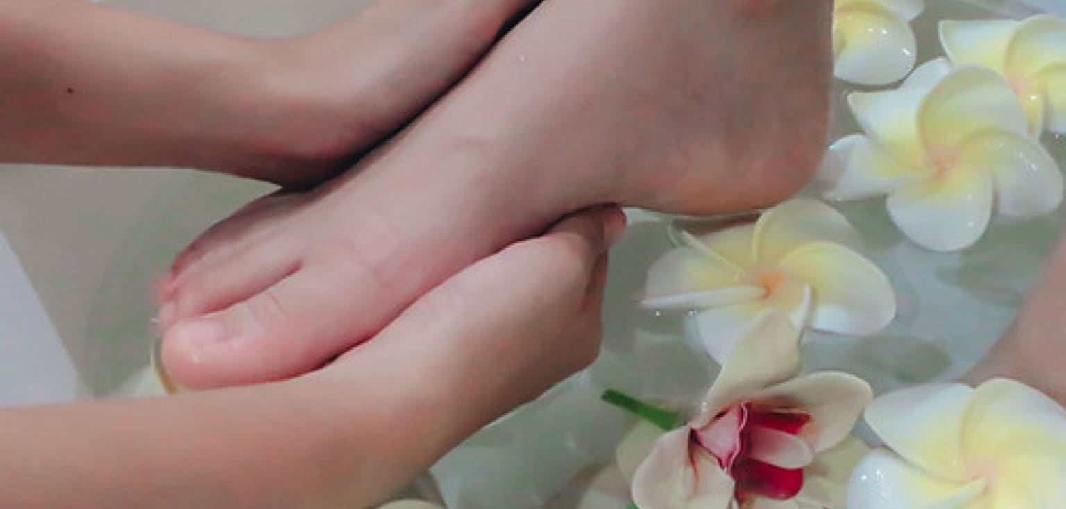Voetmassage in een voetenbad met frangipanibloemen